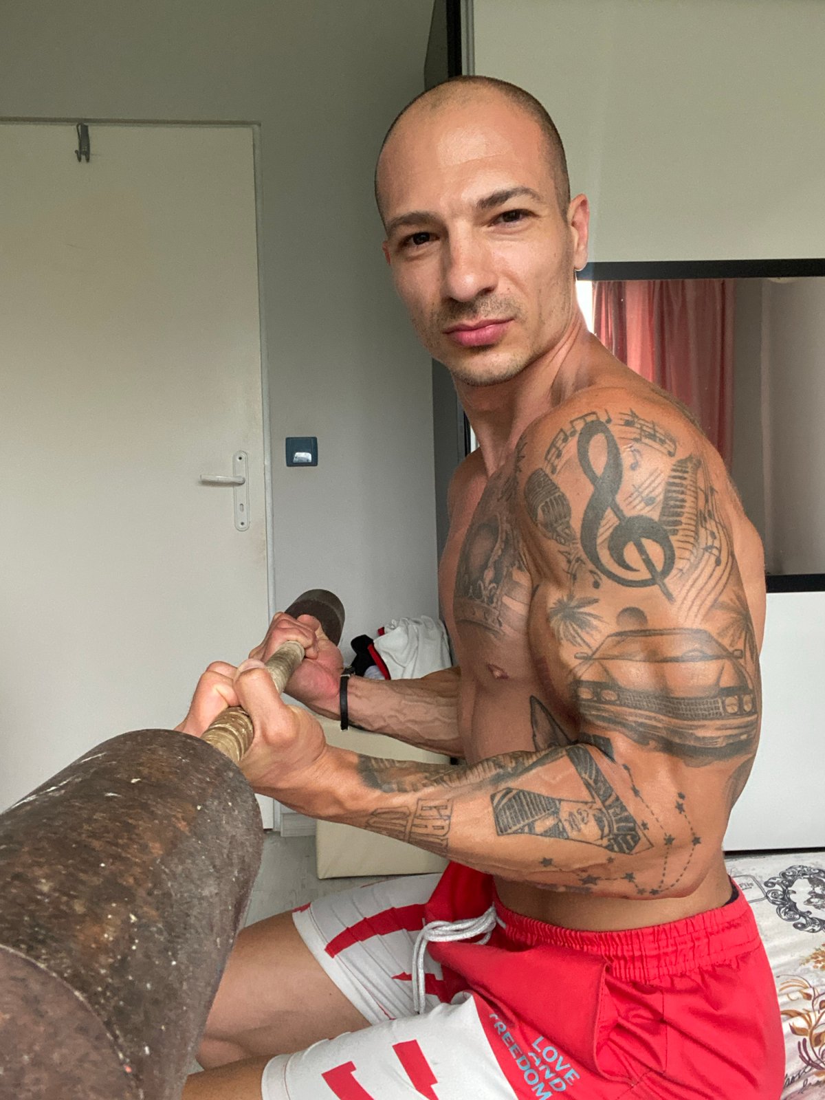 Tattooed athlete trains with weights indoors in Pleven