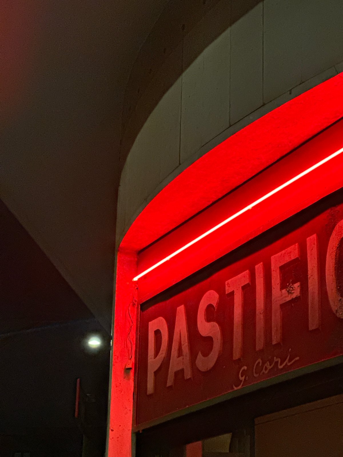 Illuminated red neon sign documented in Milan evening