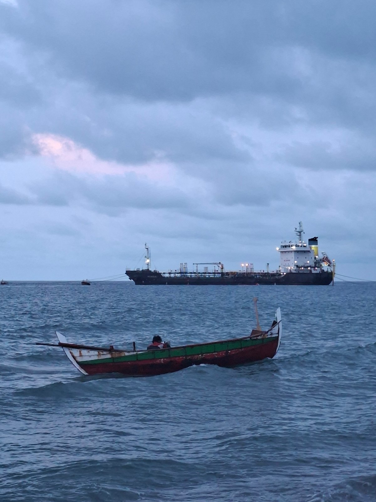 Fishing boats operate near docked tanker in Lhokseumawe port