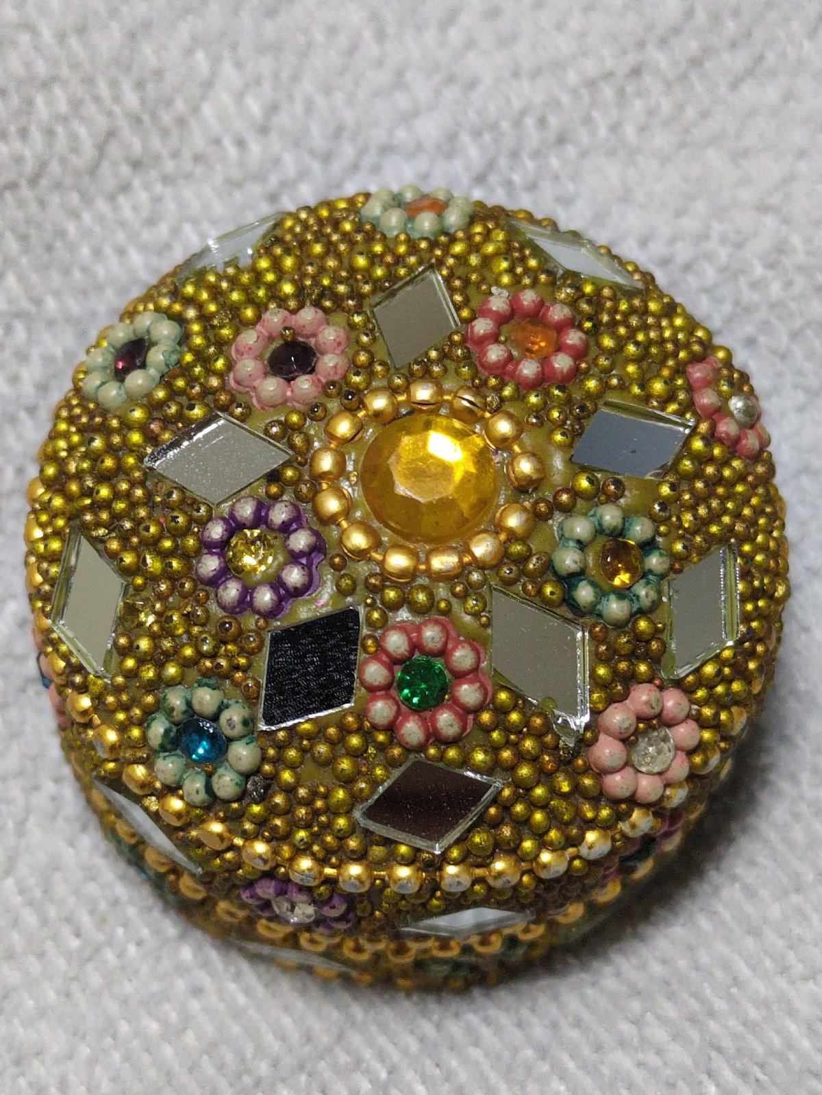 Ornate circular object with gold beads captured overhead