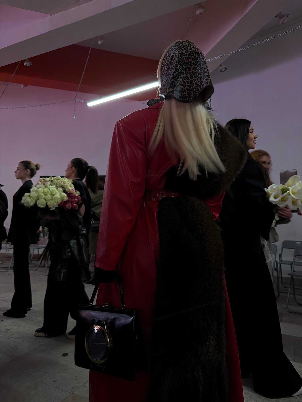 Fashion show features model in leopard headscarf, red coat