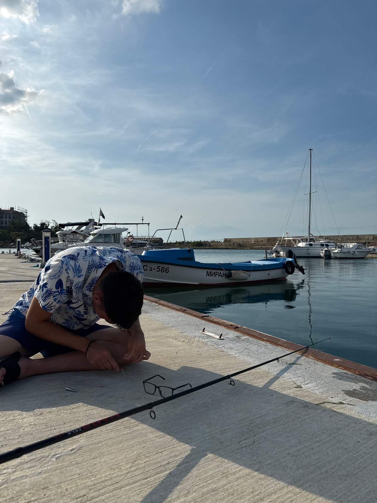 Young man fishing, kitten playing captured in Sozopol marina