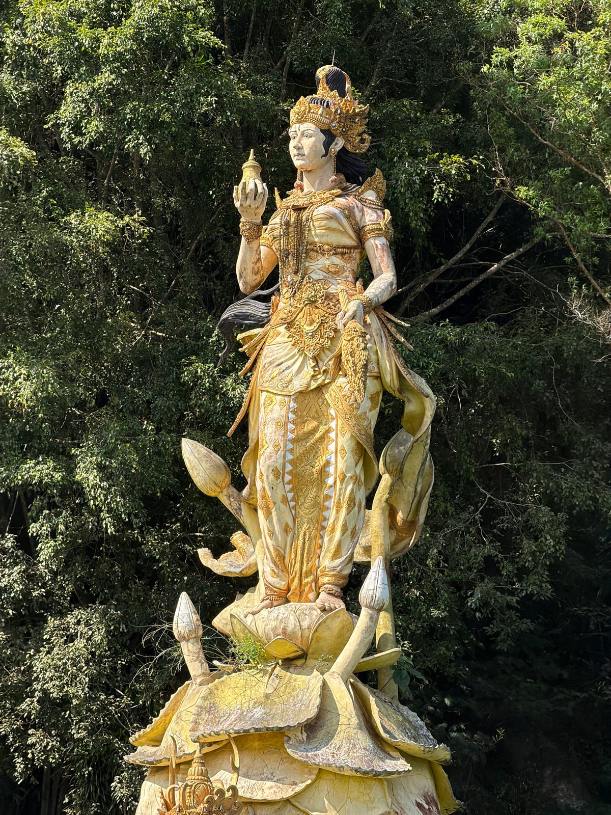 Golden statues rise from a green lake at Kintamani temple complex