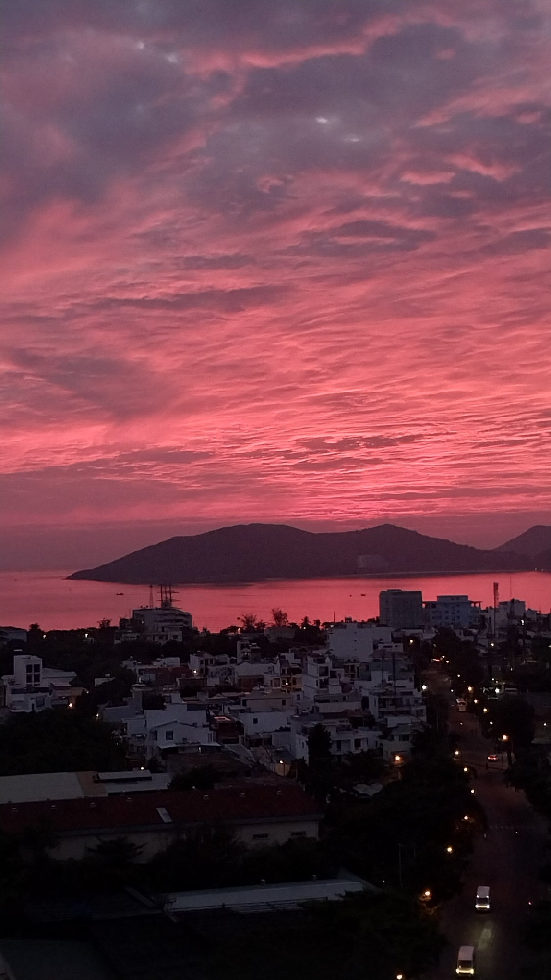 Fiery pink and red sunset lights up a coastal city skyline