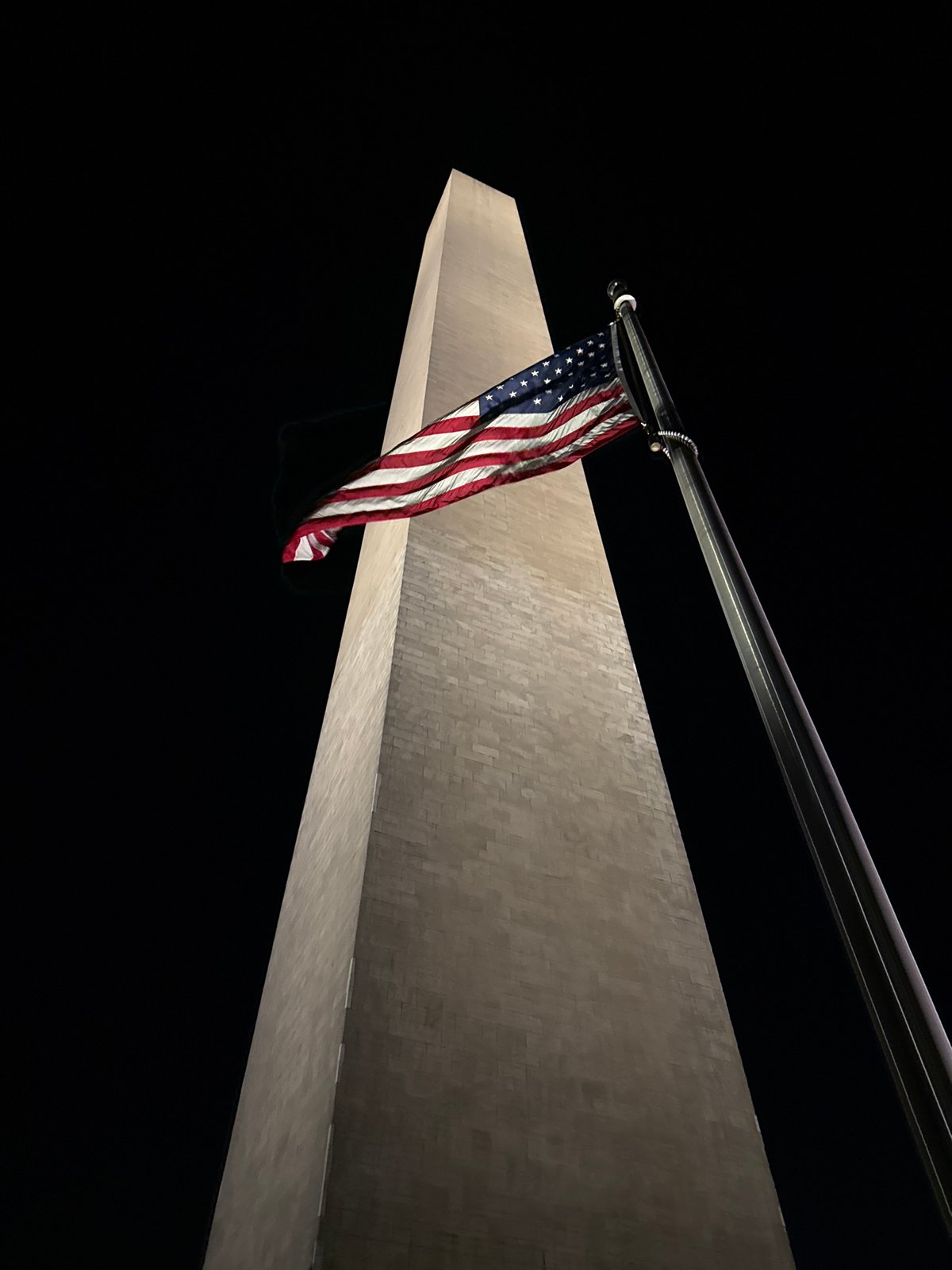 Washington Monument photographed illuminated at night with American flag