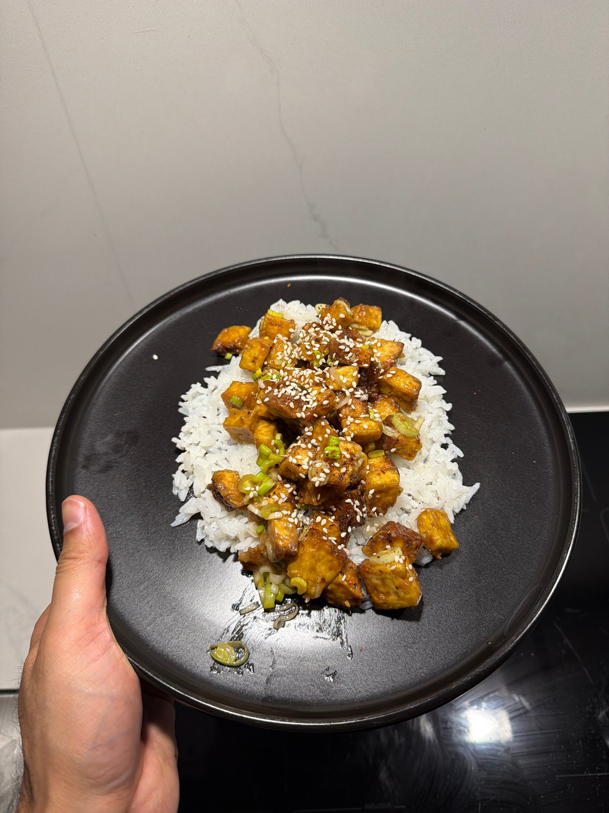 Person serves rice and glazed tofu dish in London