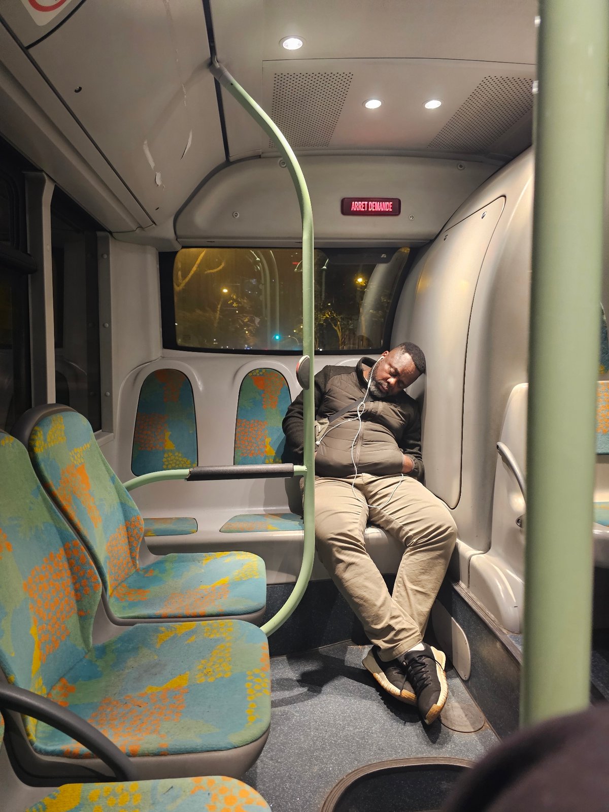 Man rests on bus seats in early morning Paris