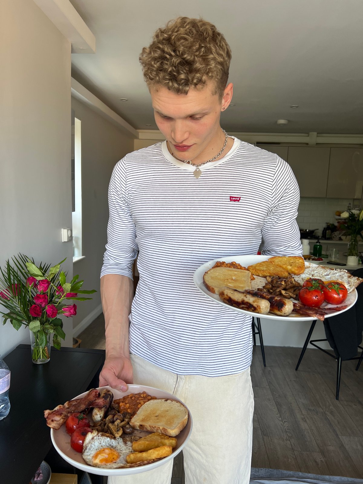 Young man holds two plates of food in London