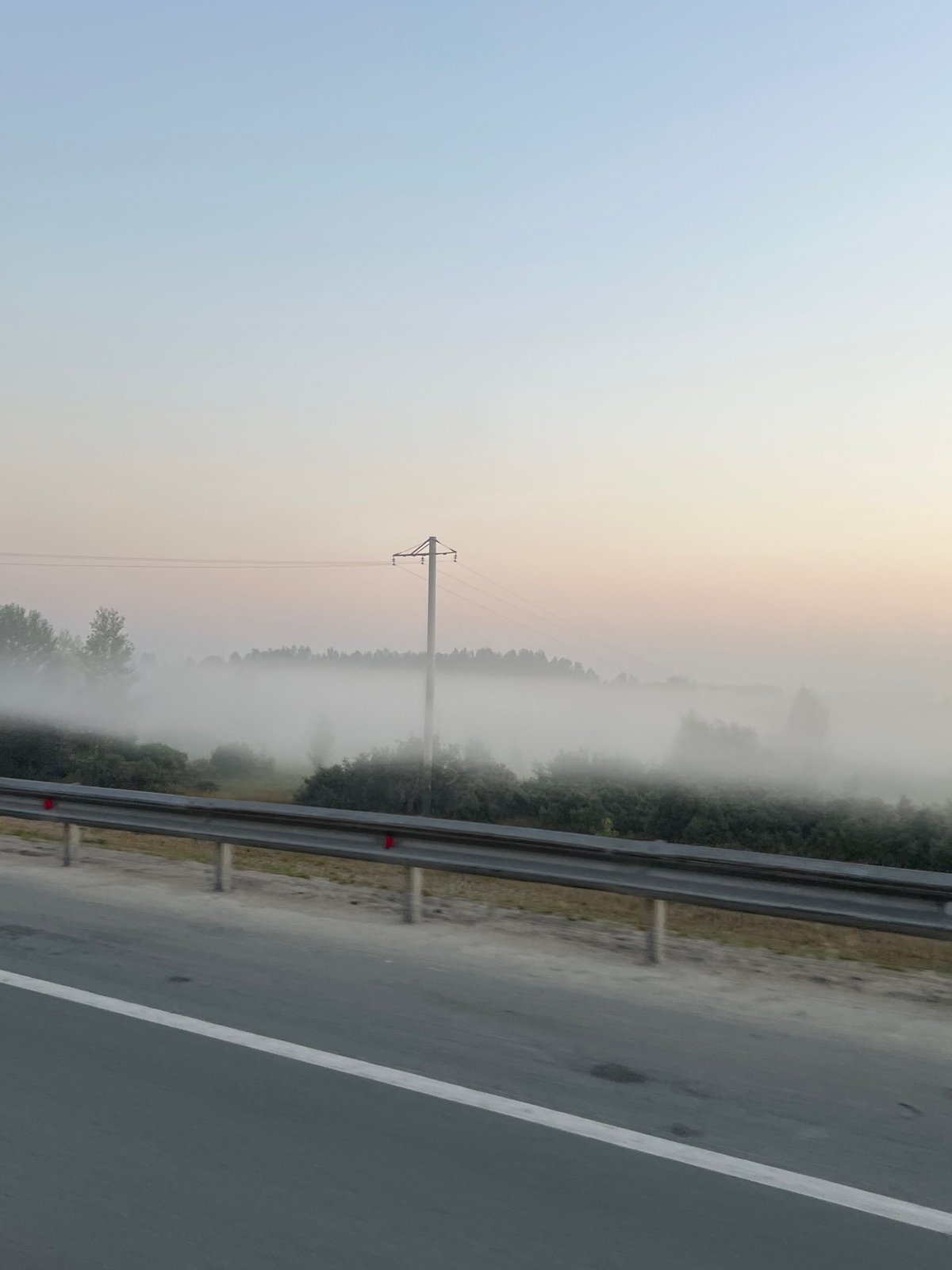 Foggy rural road with guardrail and signage, Mochishche