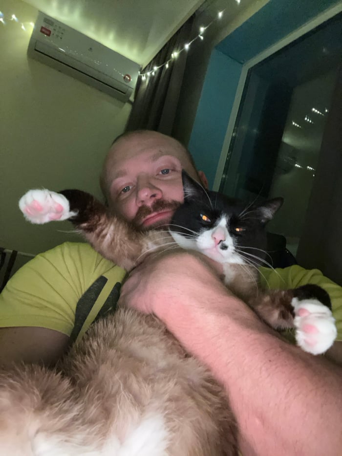 Man bonds with blue-eyed cat during evening in Russia
