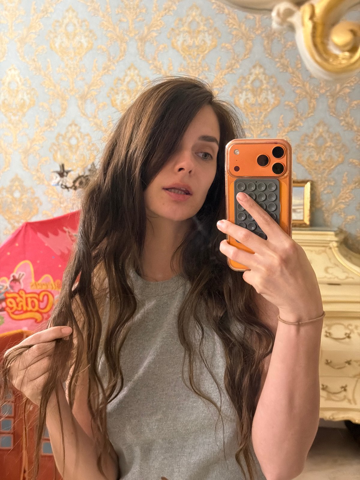 Indoor selfie with orange phone against ornate wallpaper in Ufa