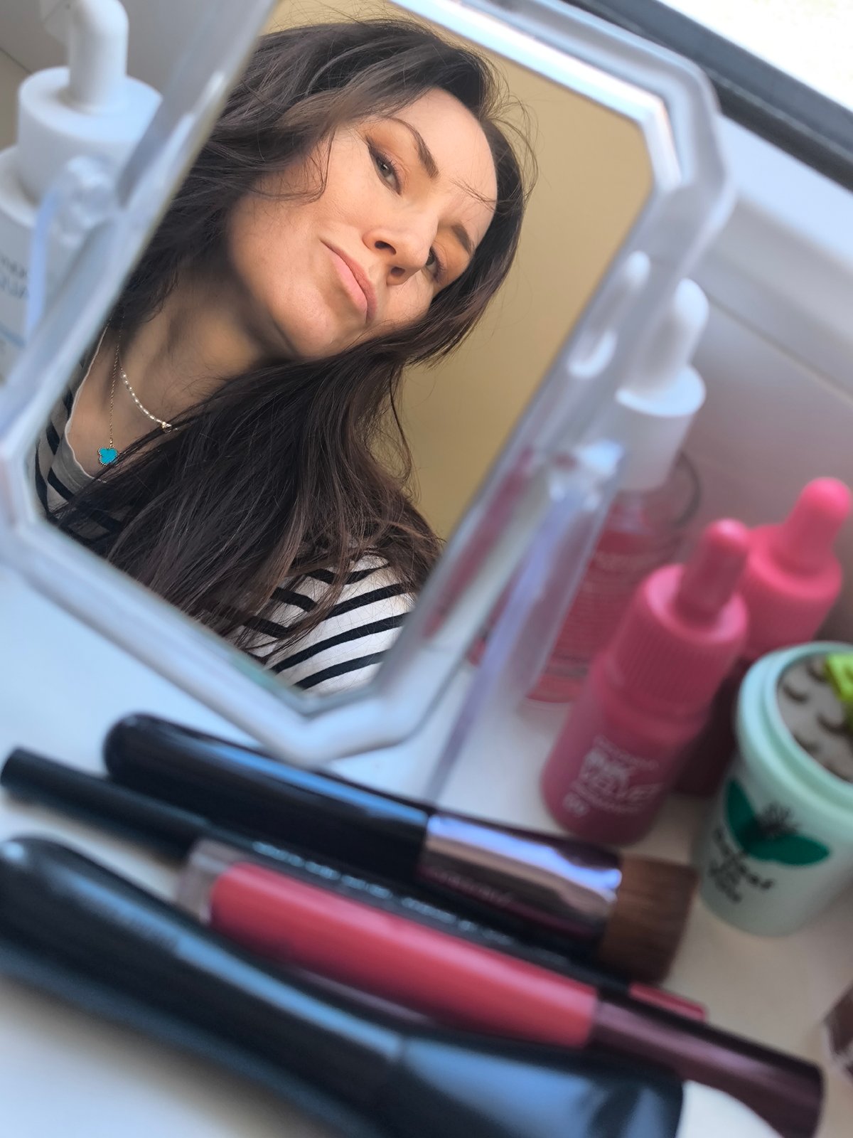 Woman applies makeup in mirror, Riga Latvia morning routine