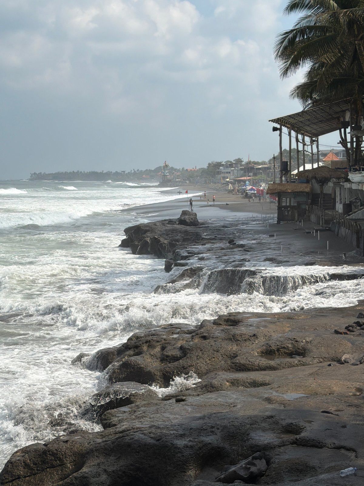 Surfers hitting the waves at North Kuta's black sand beach