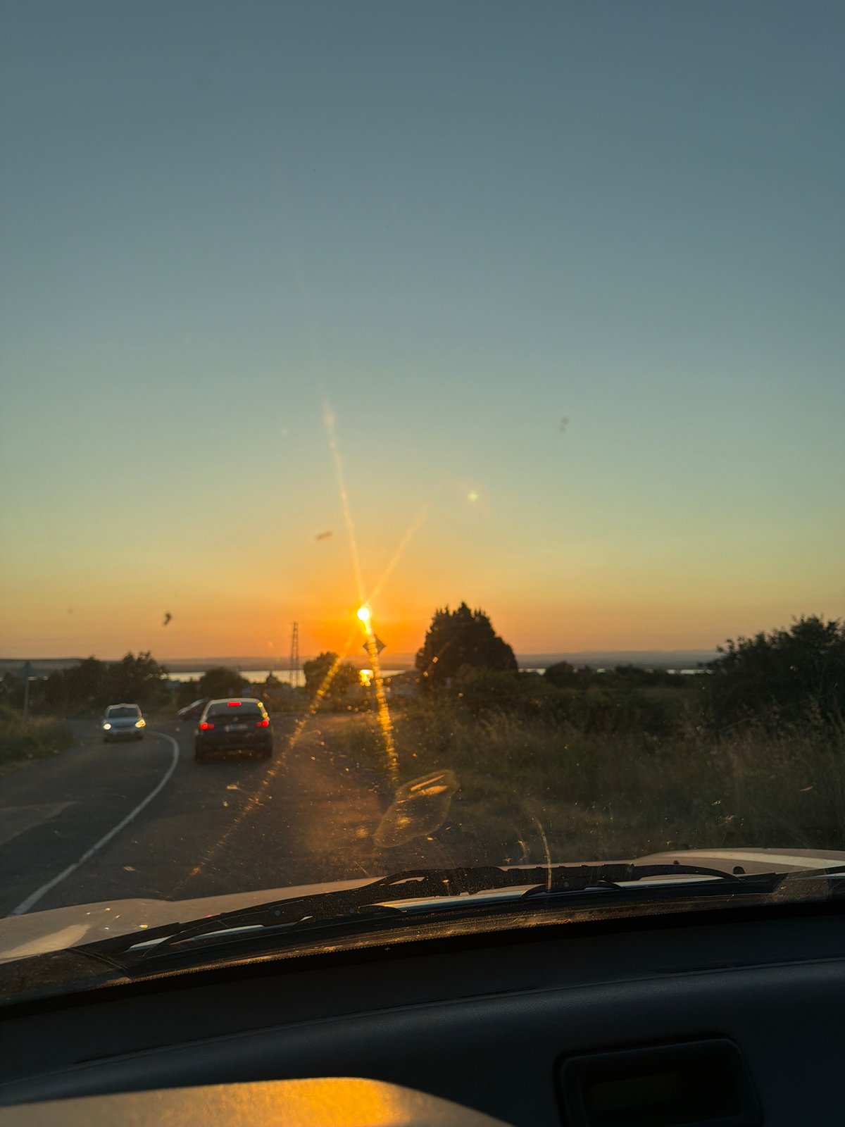 Golden sunset through a windshield, sun low on the horizon
