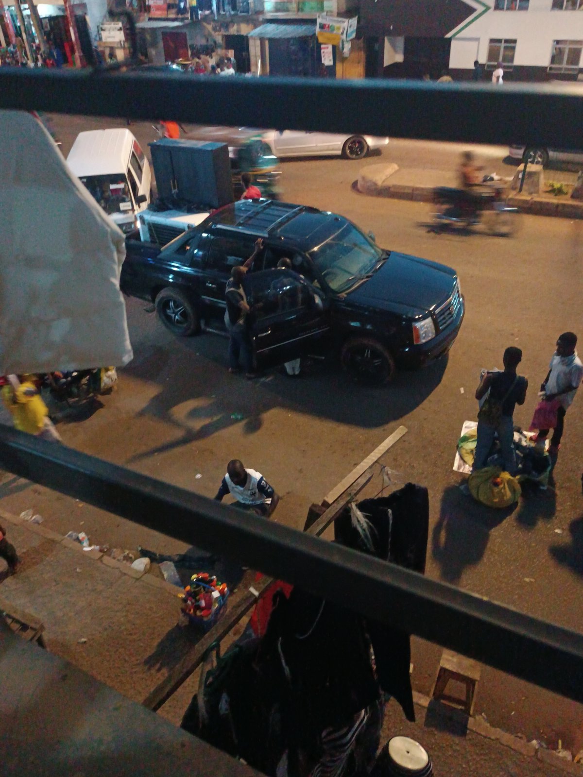 Black SUV parked at night with gathering of people
