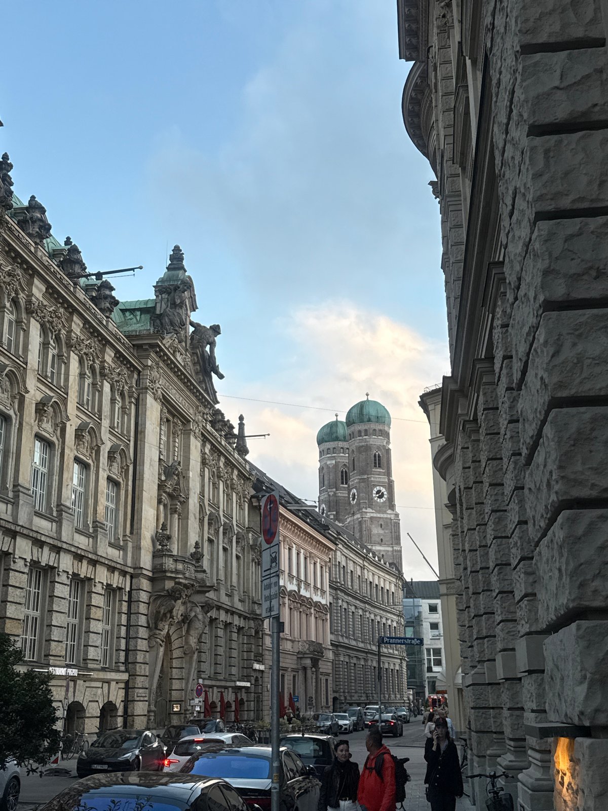 Munich street scene features Frauenkirche cathedral towers