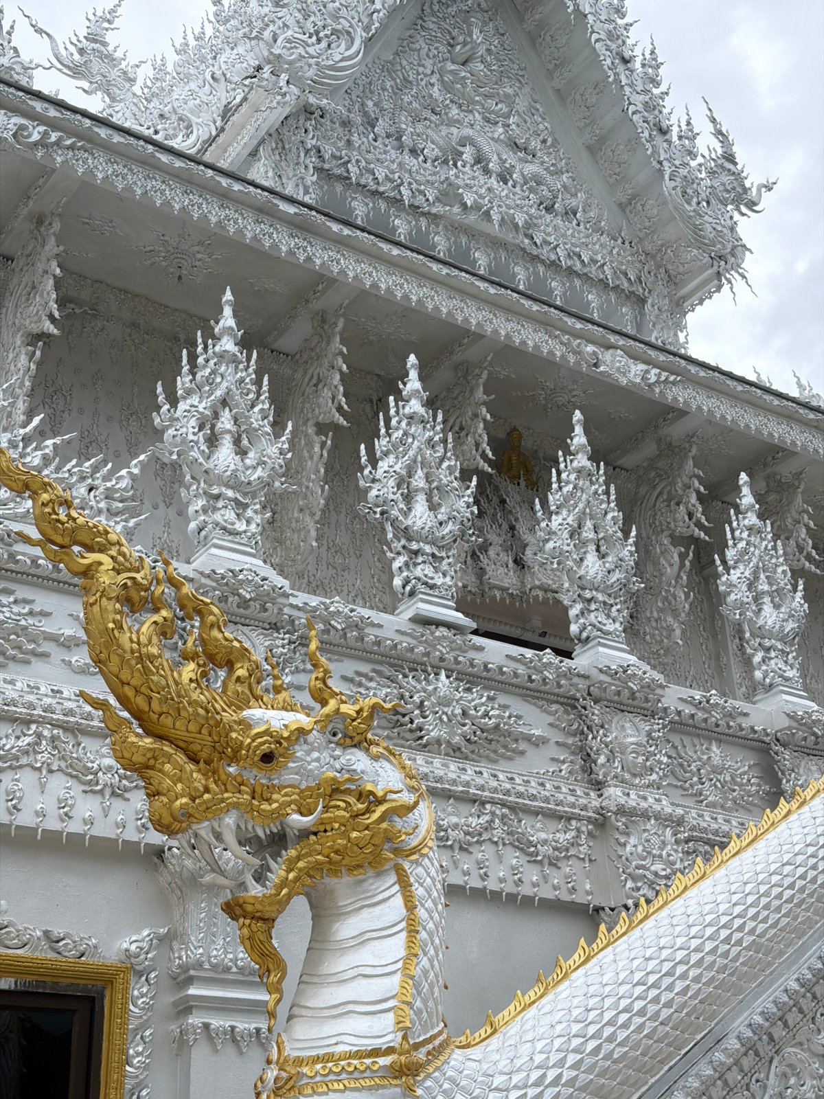 Visitor documents Thailand's White Temple from multiple angles during rainstorm