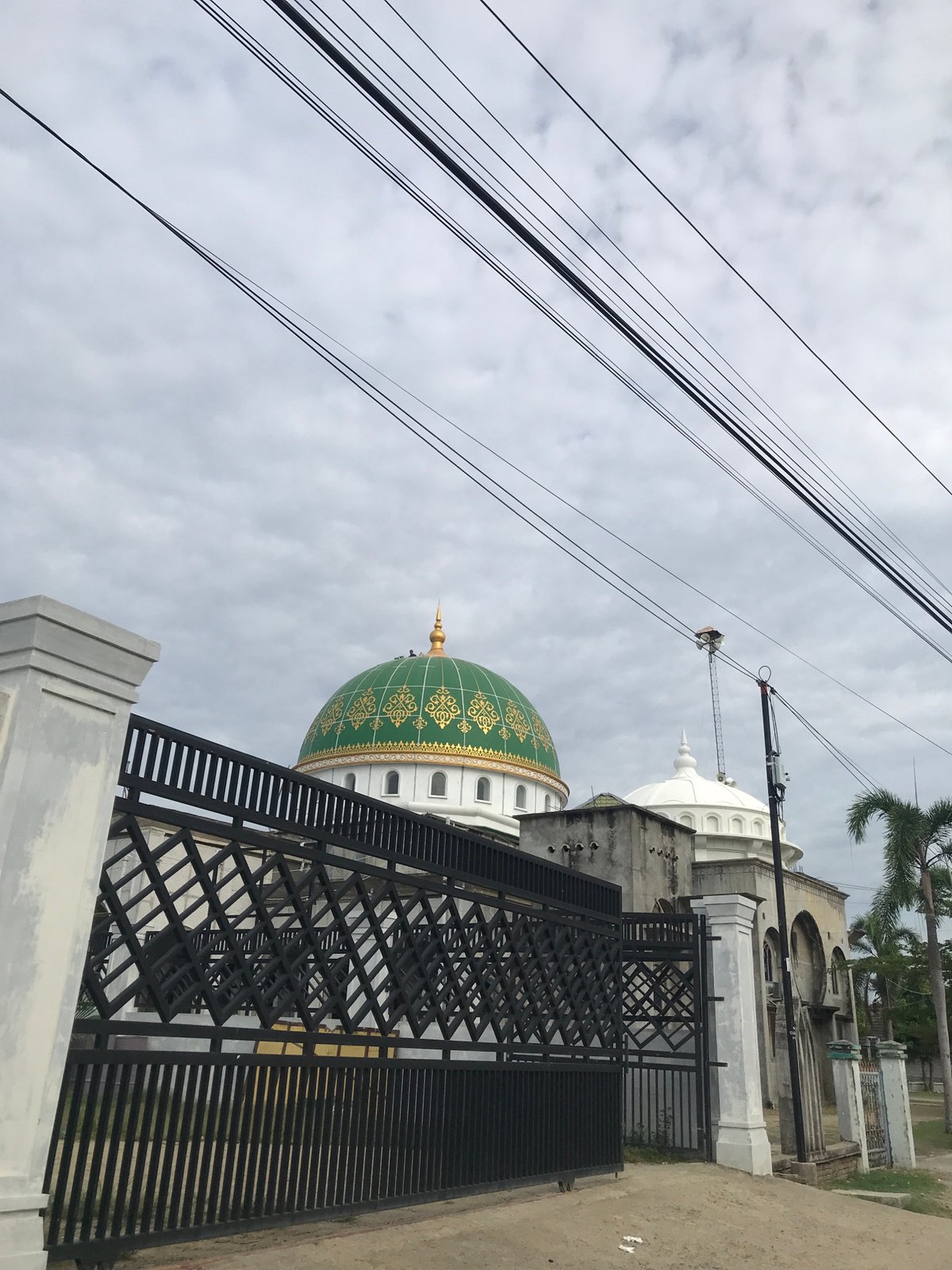 Islamic Center Lhokseumawe mosque viewed through metal fence