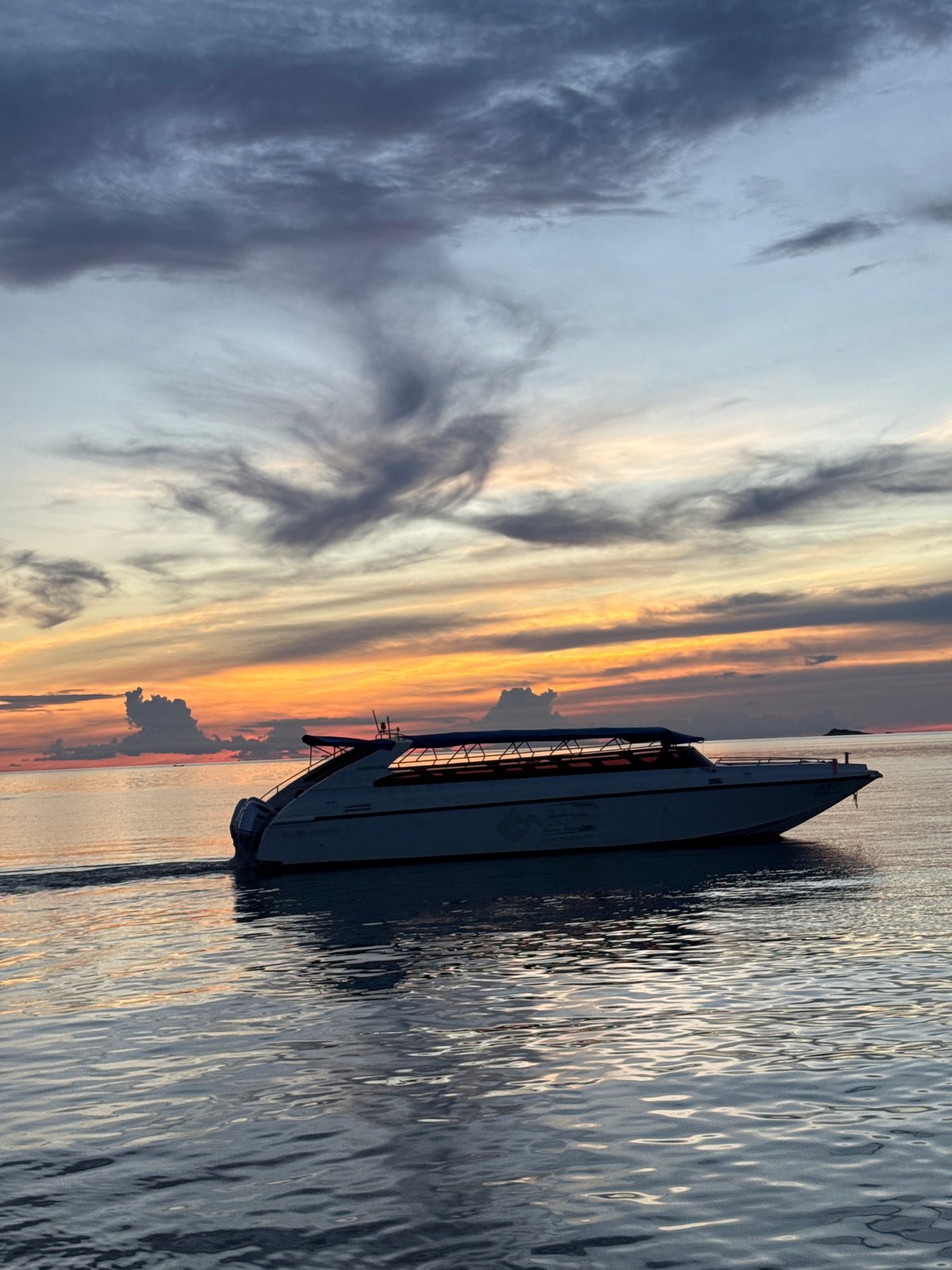 Boats cross calm Koh Phangan waters at twilight