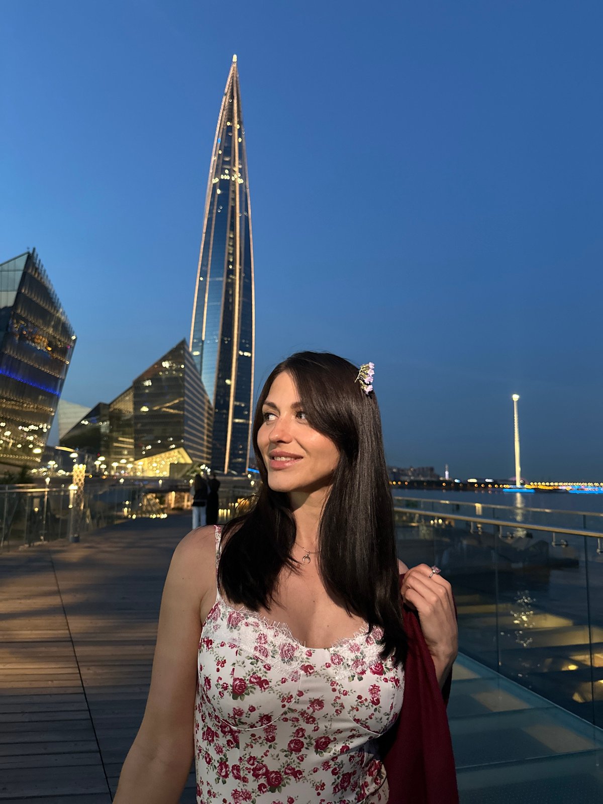 Woman in floral attire observed on Russian pier at dusk