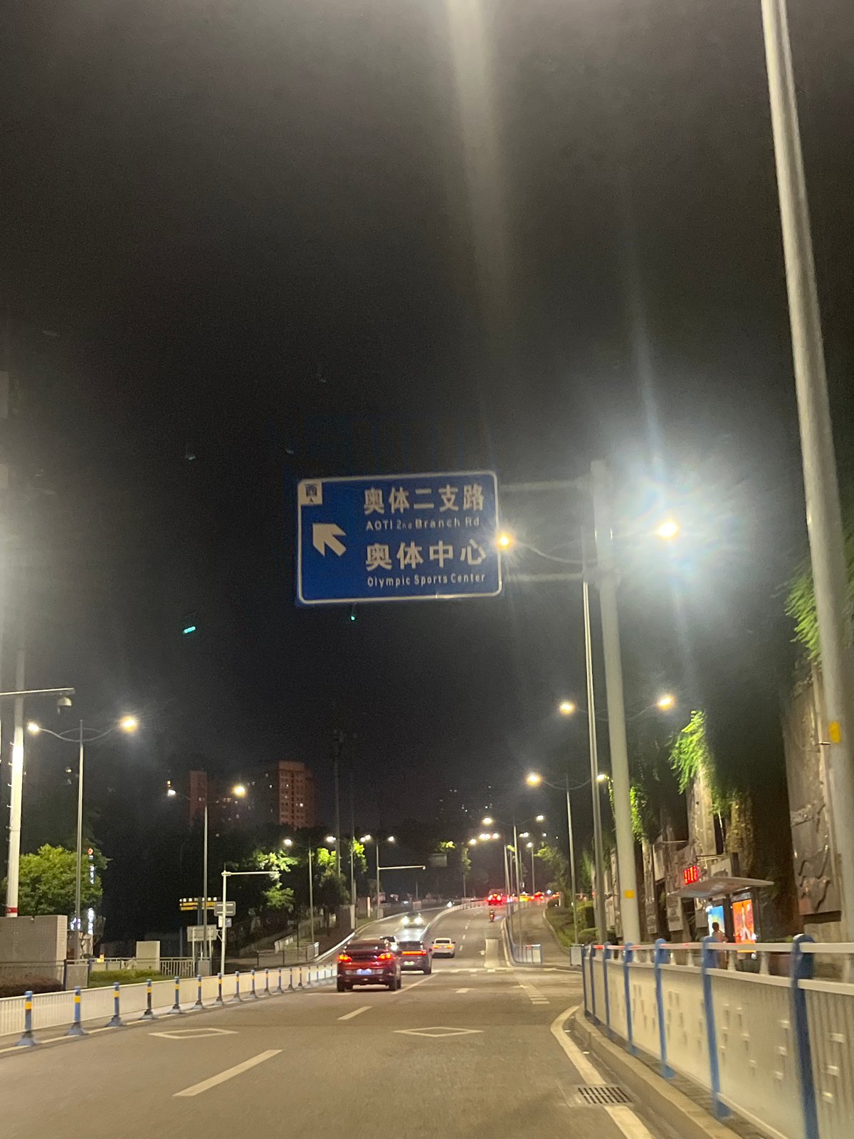 Nighttime scooter traffic documented on Chongqing streets near Olympic Sports Center