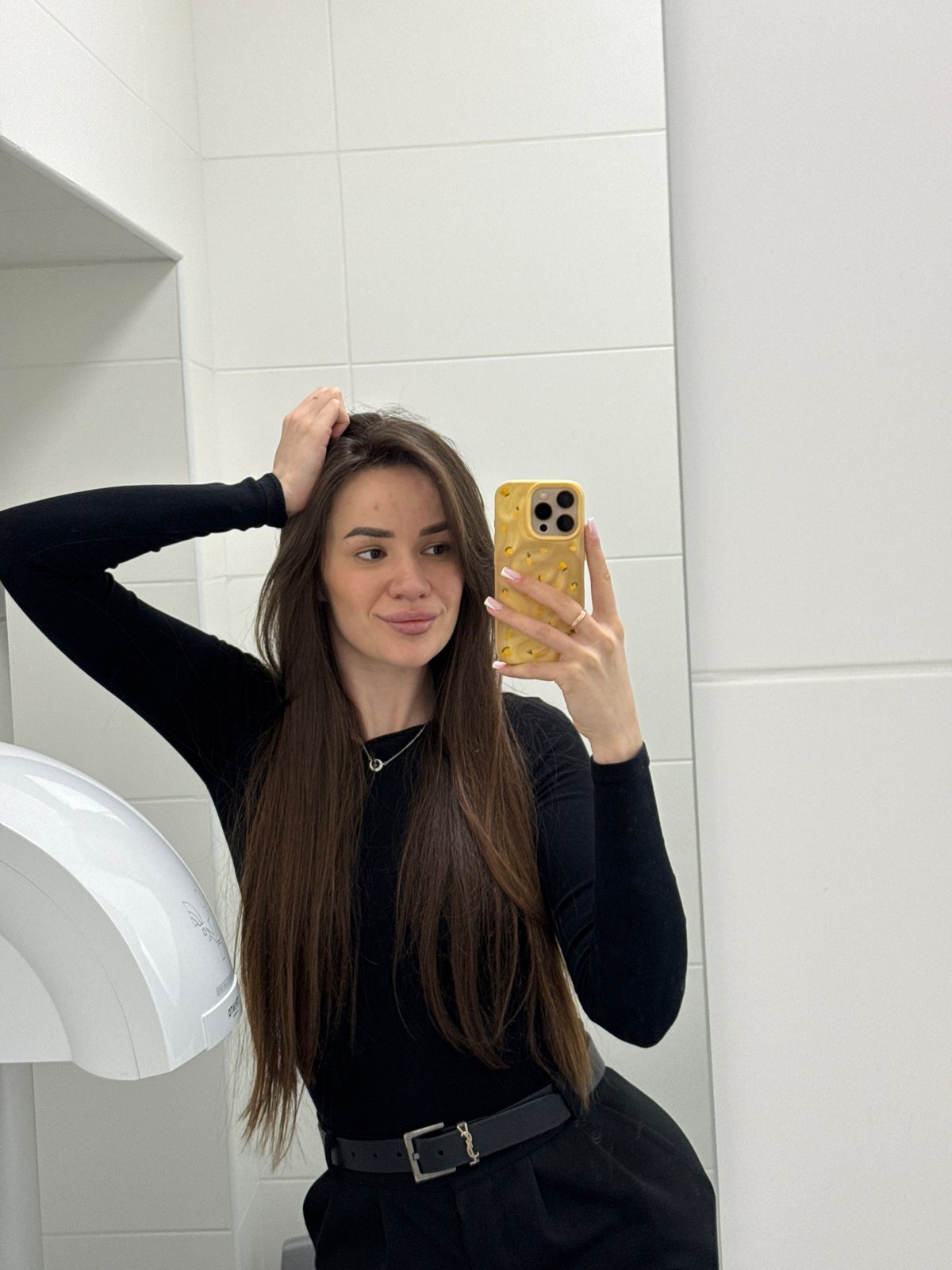 Back-to-back selfies in a restroom and elevator, same black outfit.