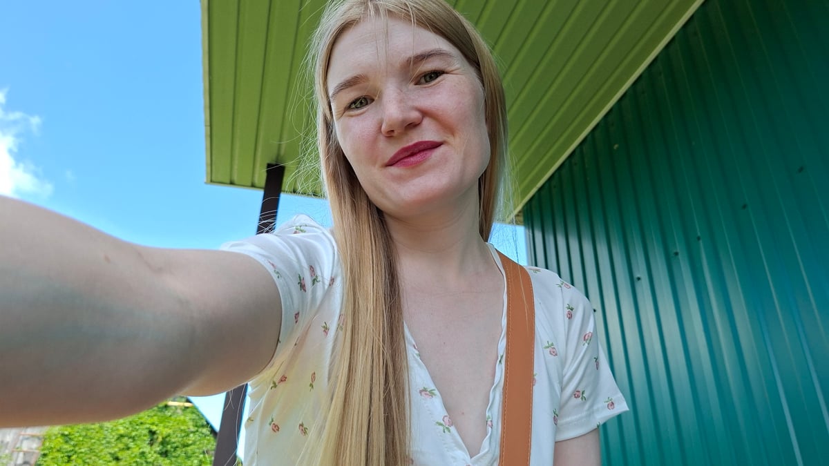 Woman takes selfies with child, pinwheel in Russian village