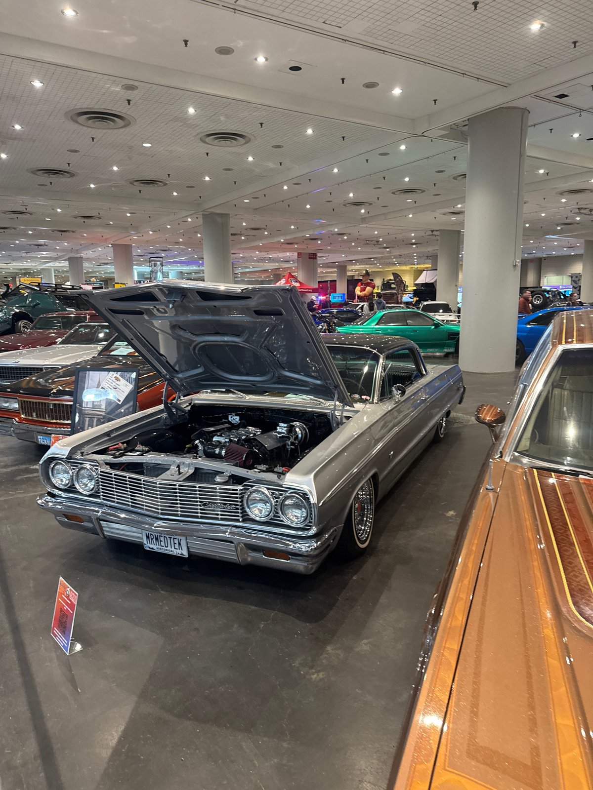 Classic car displayed with open hood at indoor auto show
