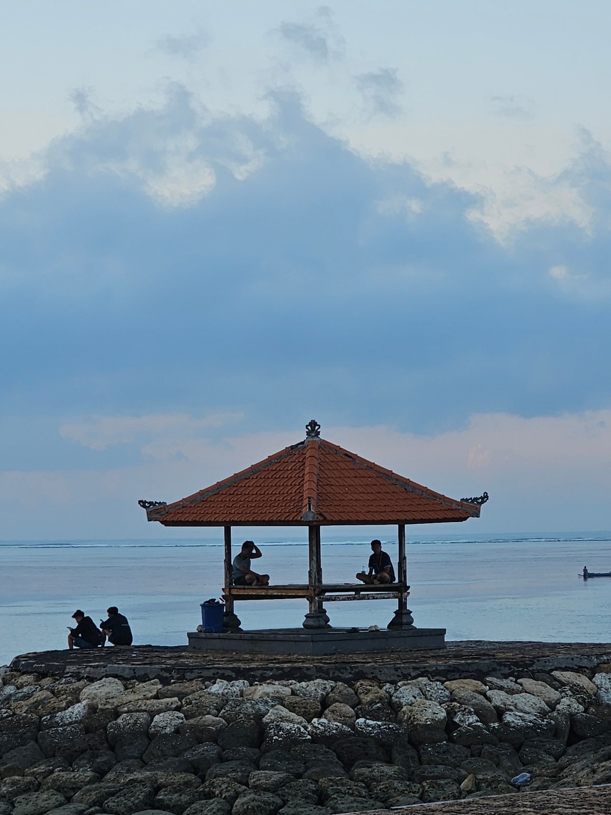 Bali beach at dusk: boats, pavilions, and a fading sky