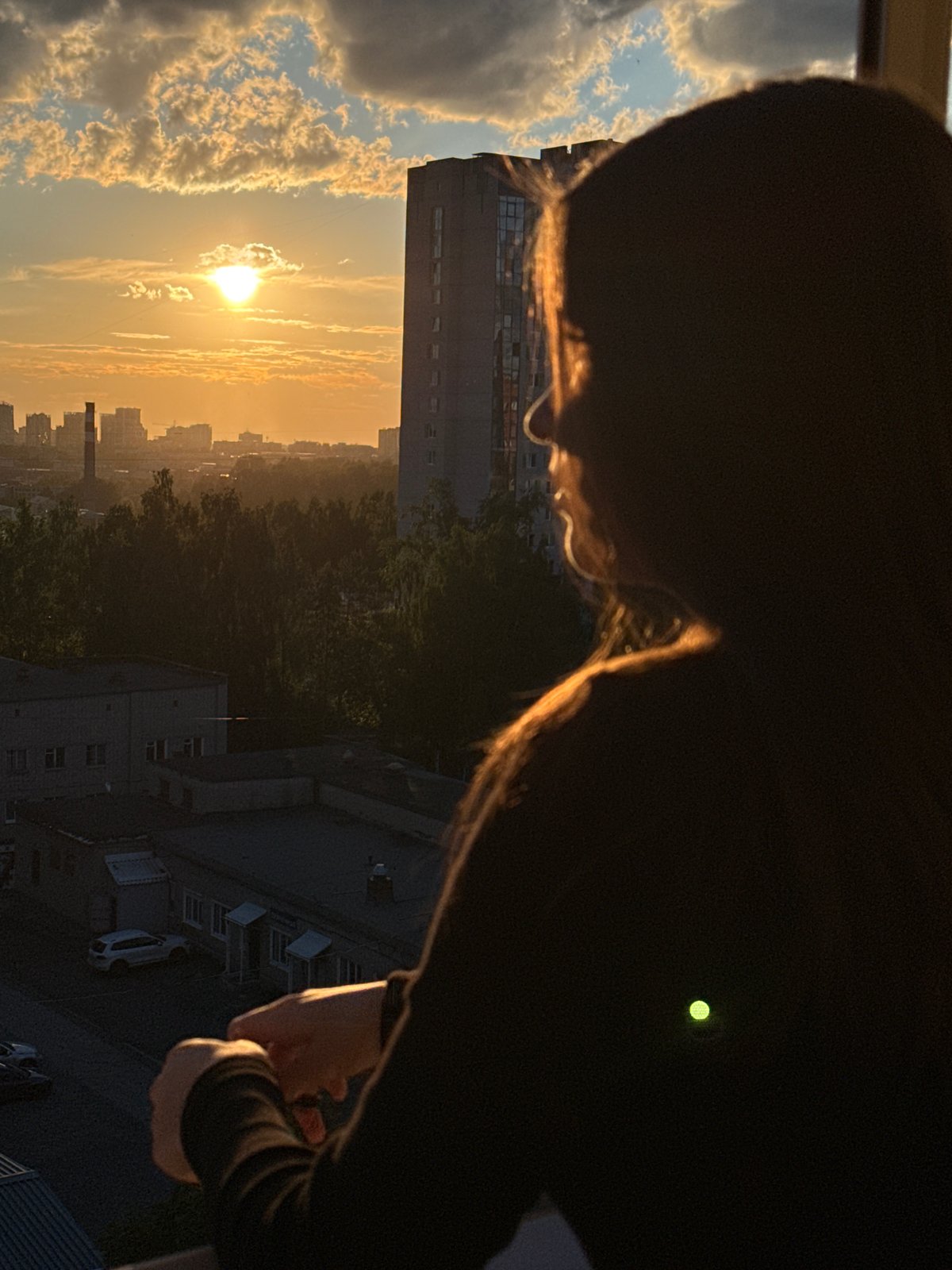 Person watches sunset over Izhevsk from high window