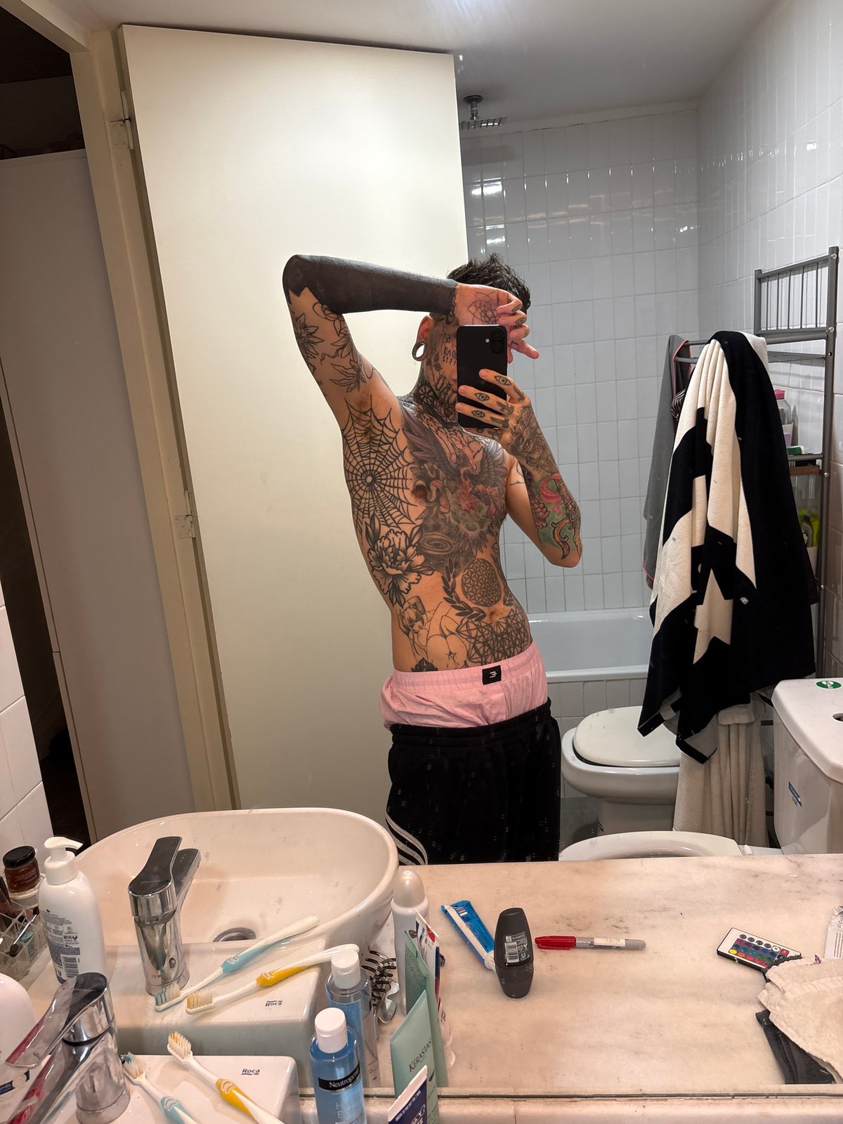 Tattooed individual takes multiple selfies in Buenos Aires residence