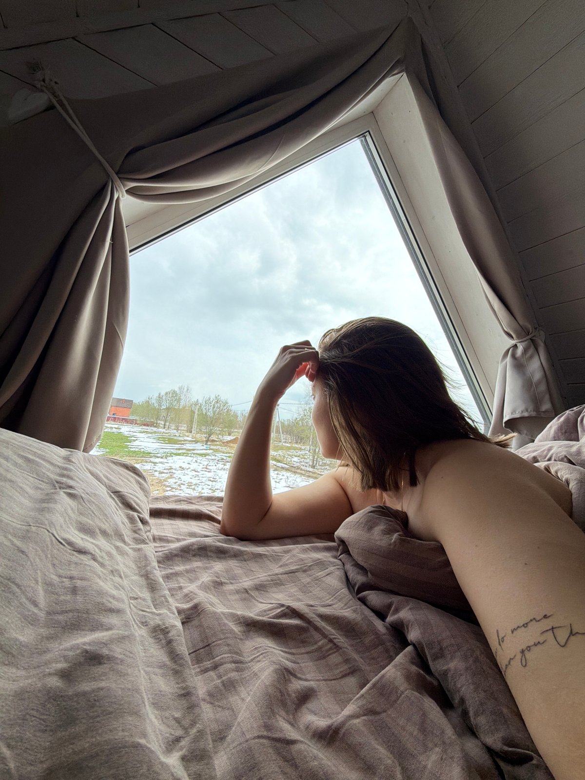 Person rests in bed on overcast morning in Бунятино