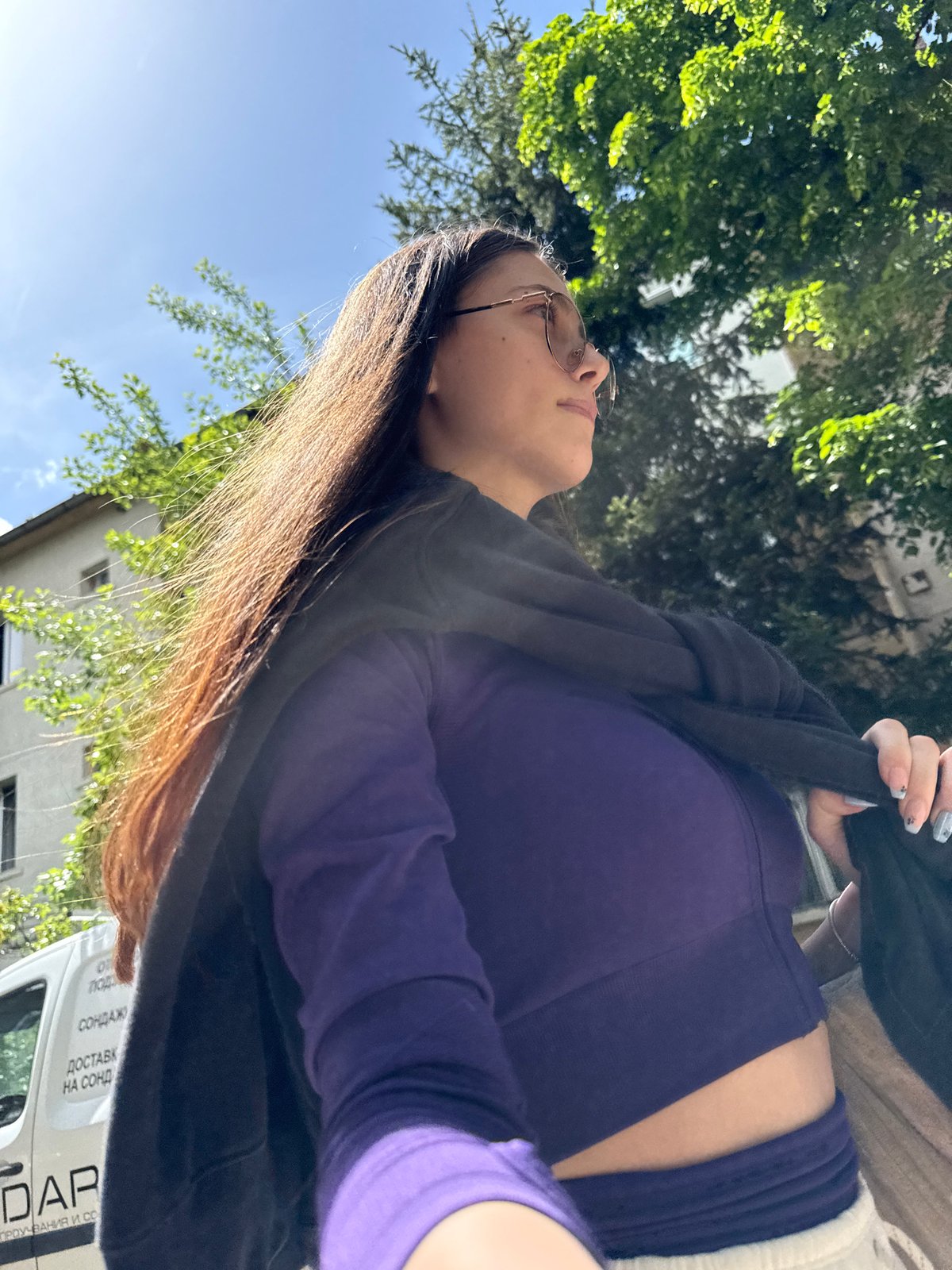 Woman looks skyward while standing under trees in Sofia
