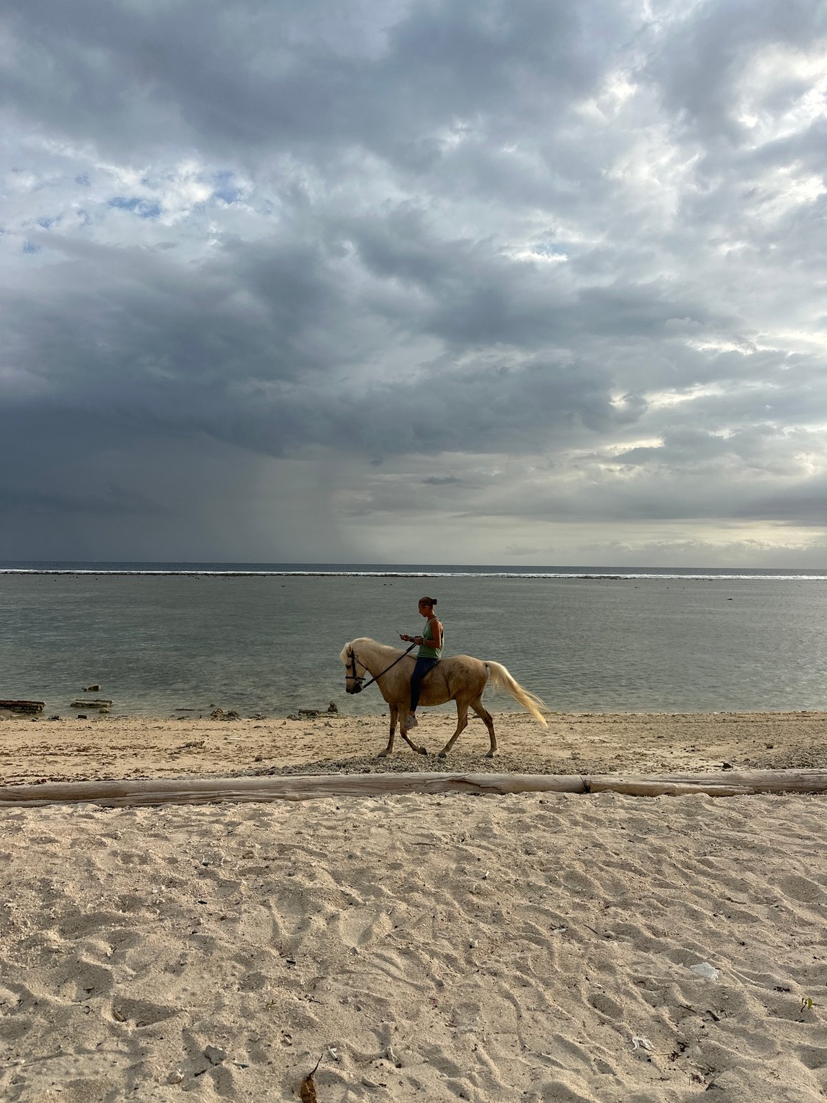 Horse rider enjoys beach outing under cloudy Indonesian skies