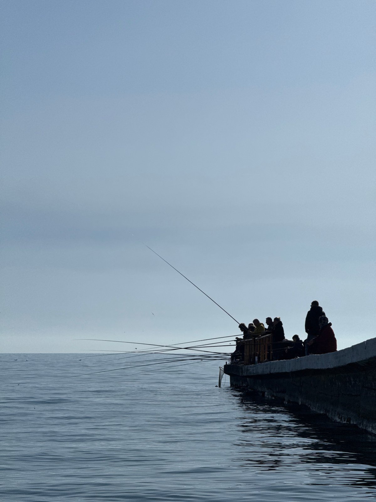 Peaceful afternoon gathering at waterfront pier draws fishers, beachgoers