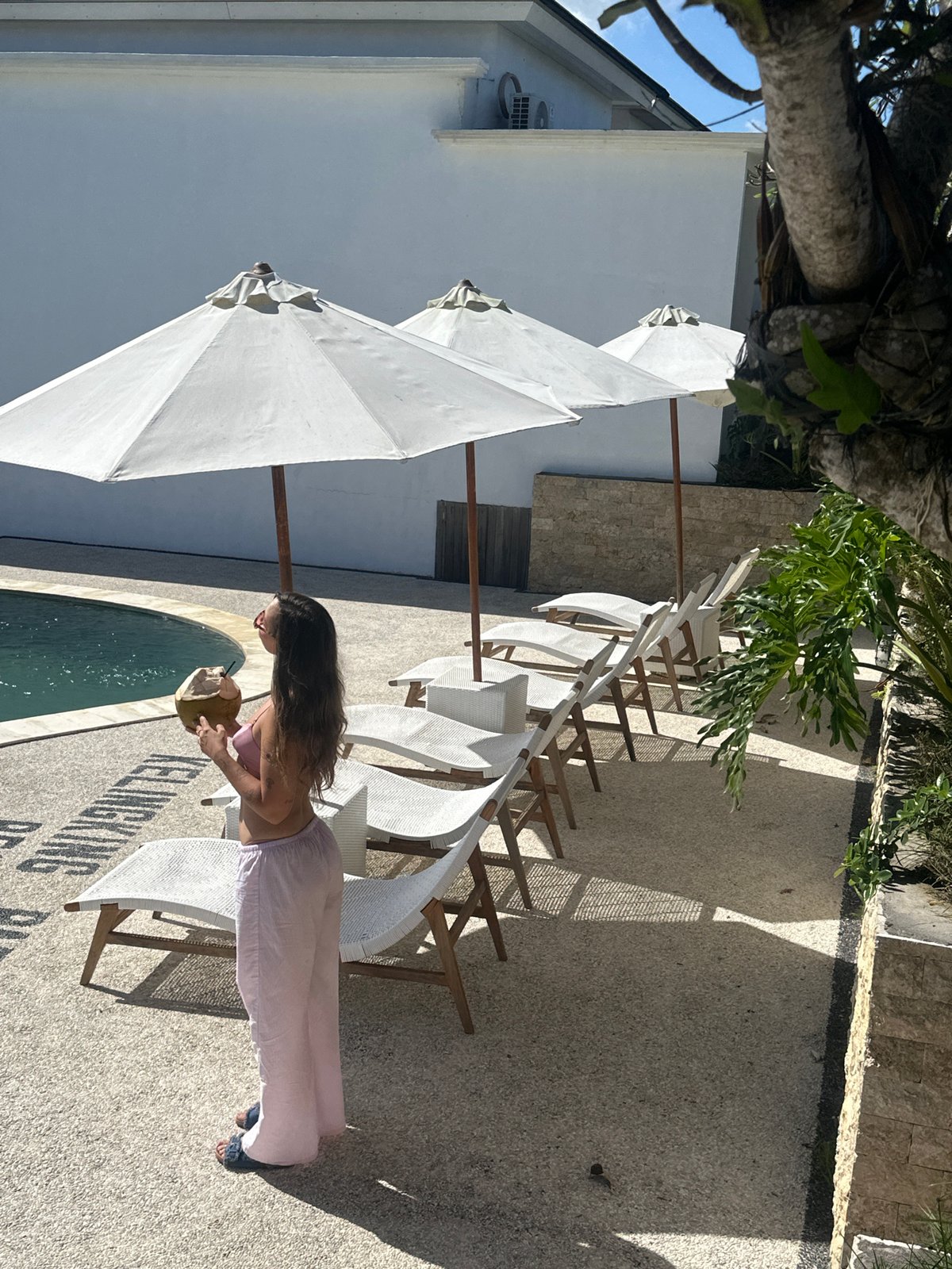 Woman enjoys coconut drink poolside in Nusa Penida morning