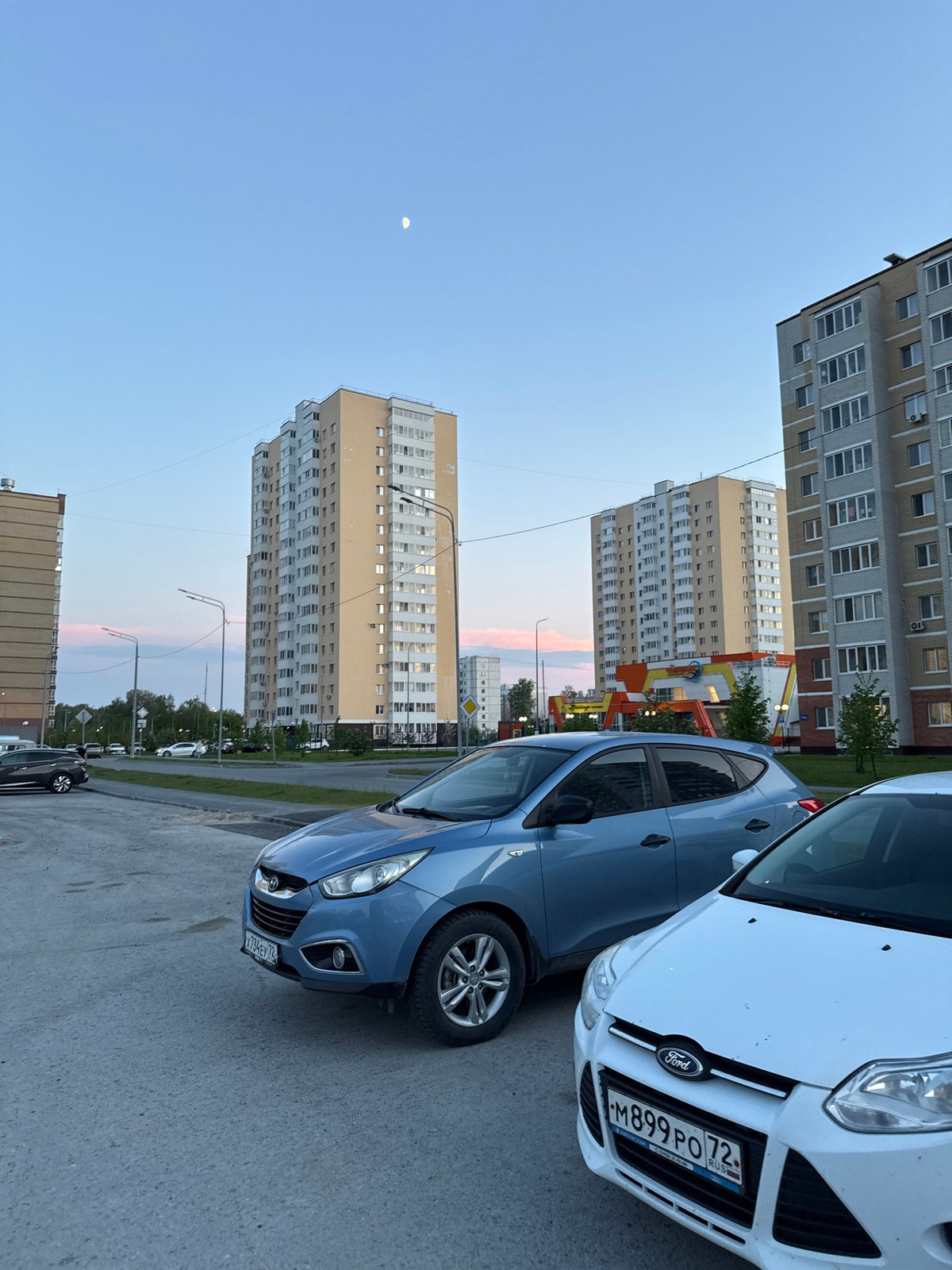 Daytime crescent moon visible over Tobolsk apartment complex