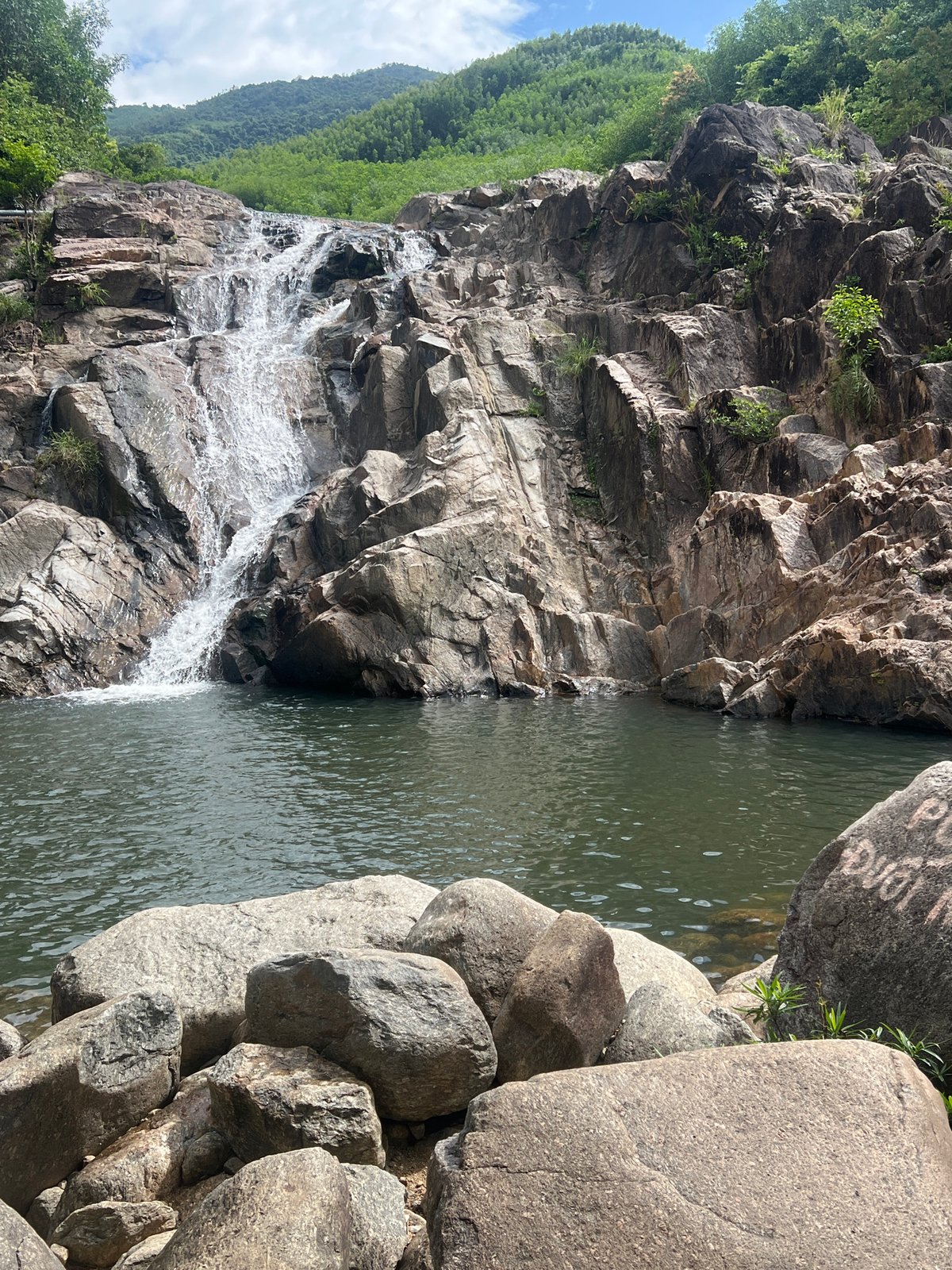 Waterfall spills into a still green pool near Đà Nẵng