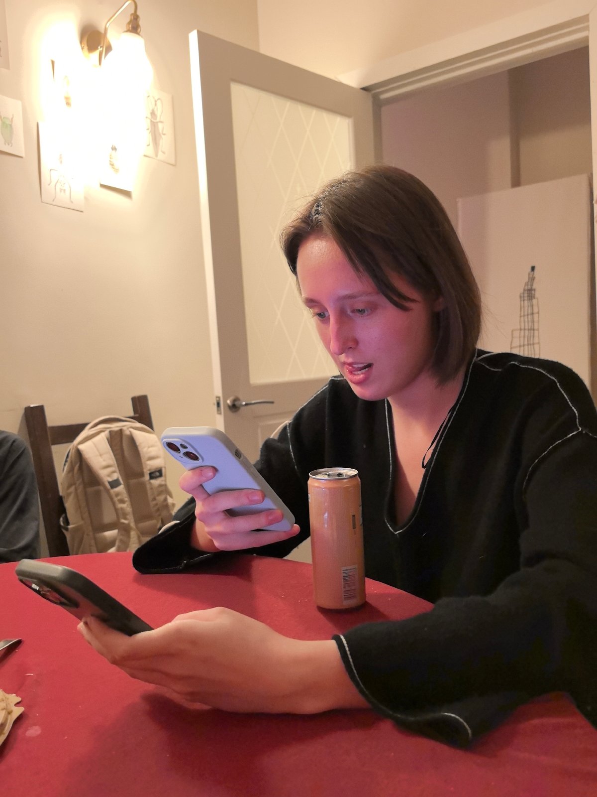 Person Uses Two Smartphones Simultaneously at Indoor Red Table