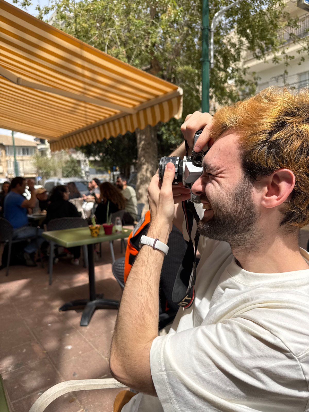 Man with vintage camera captured amid artwork and cake