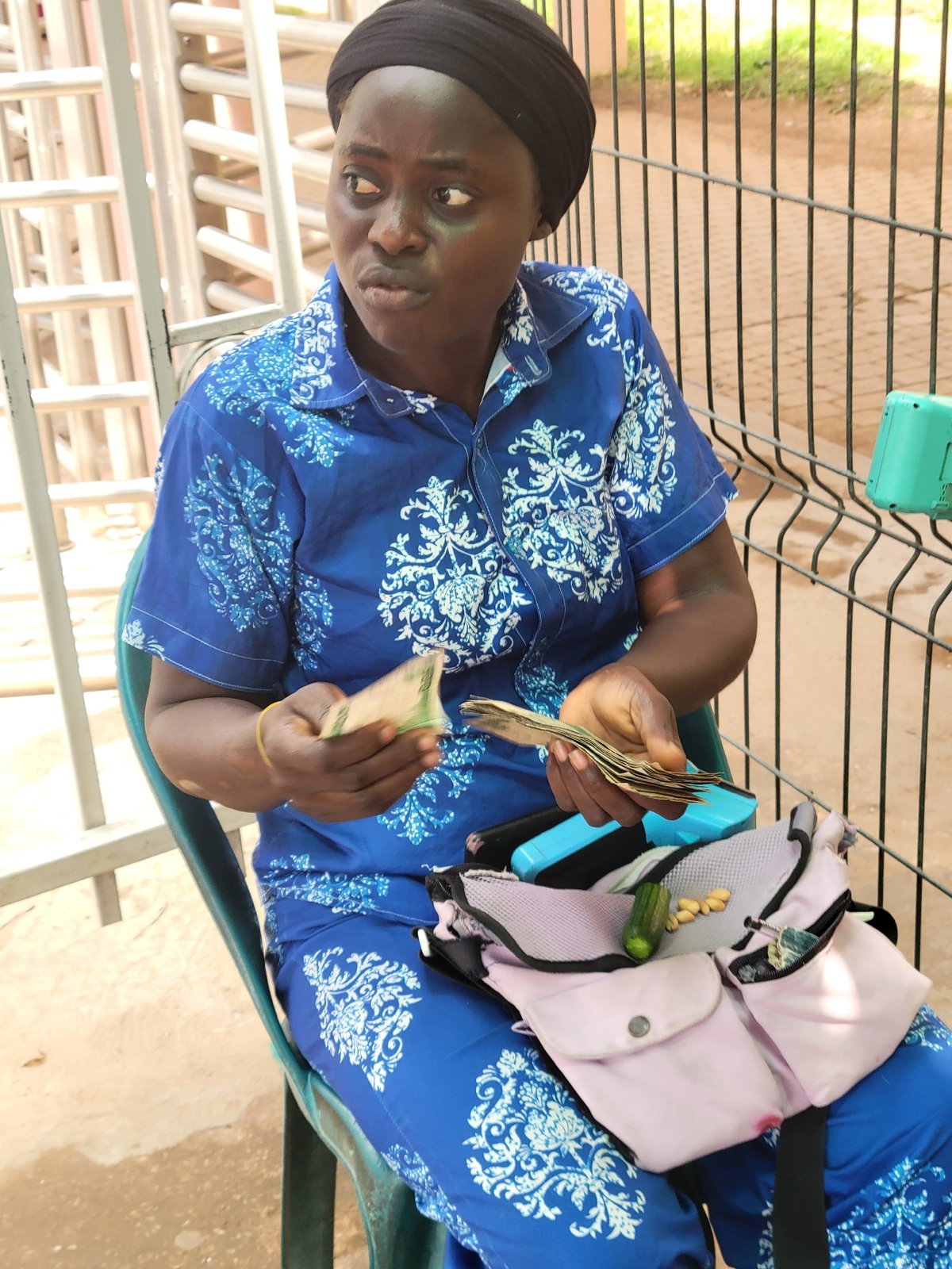 Woman counts currency, uses phone in Abuja street scene