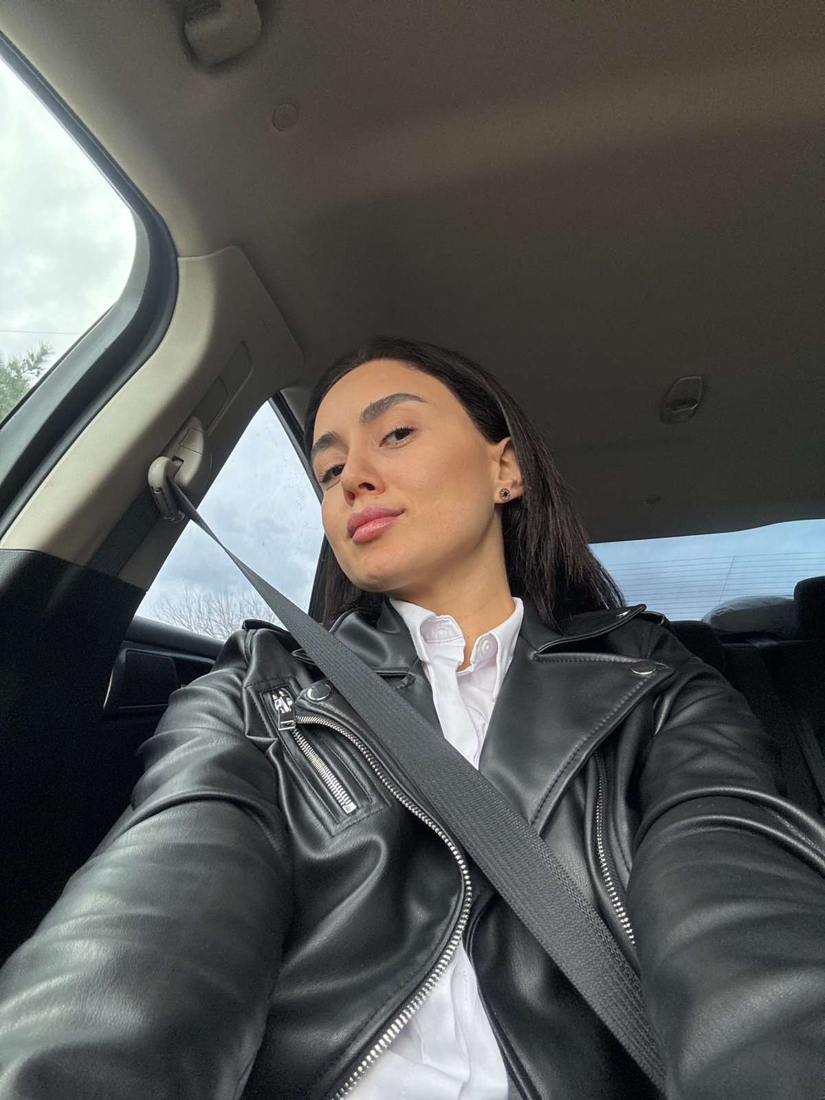 Person photographed in car wearing leather jacket in Tbilisi