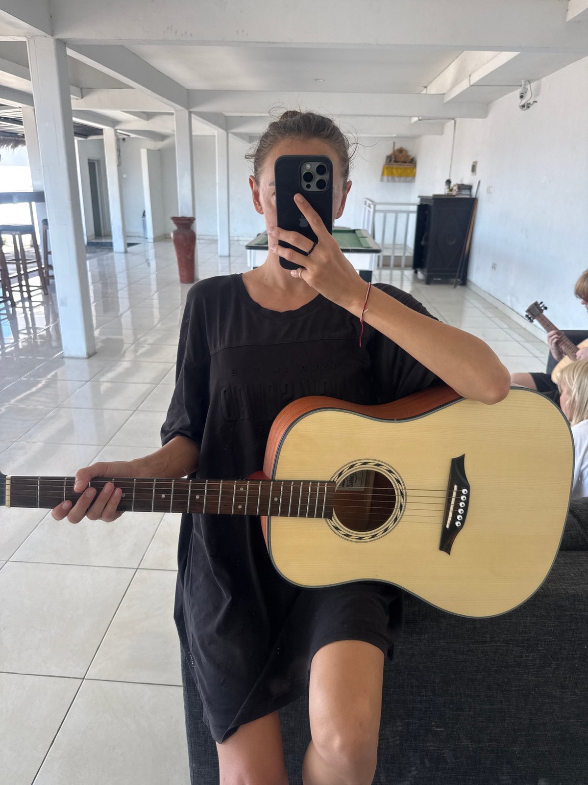 Person takes mirror selfie with acoustic guitar in Kuta