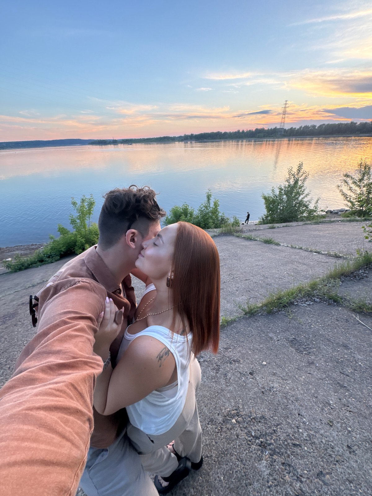 Couple shares romantic sunset moment by Russian riverside lighthouse