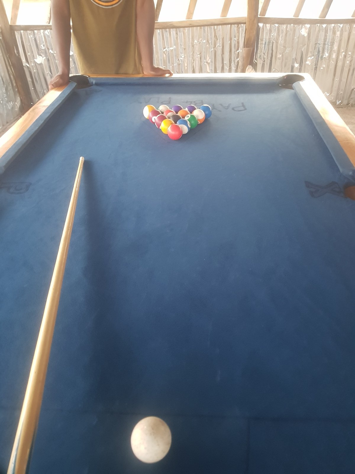 Pool game at a rustic open-air billiard table
