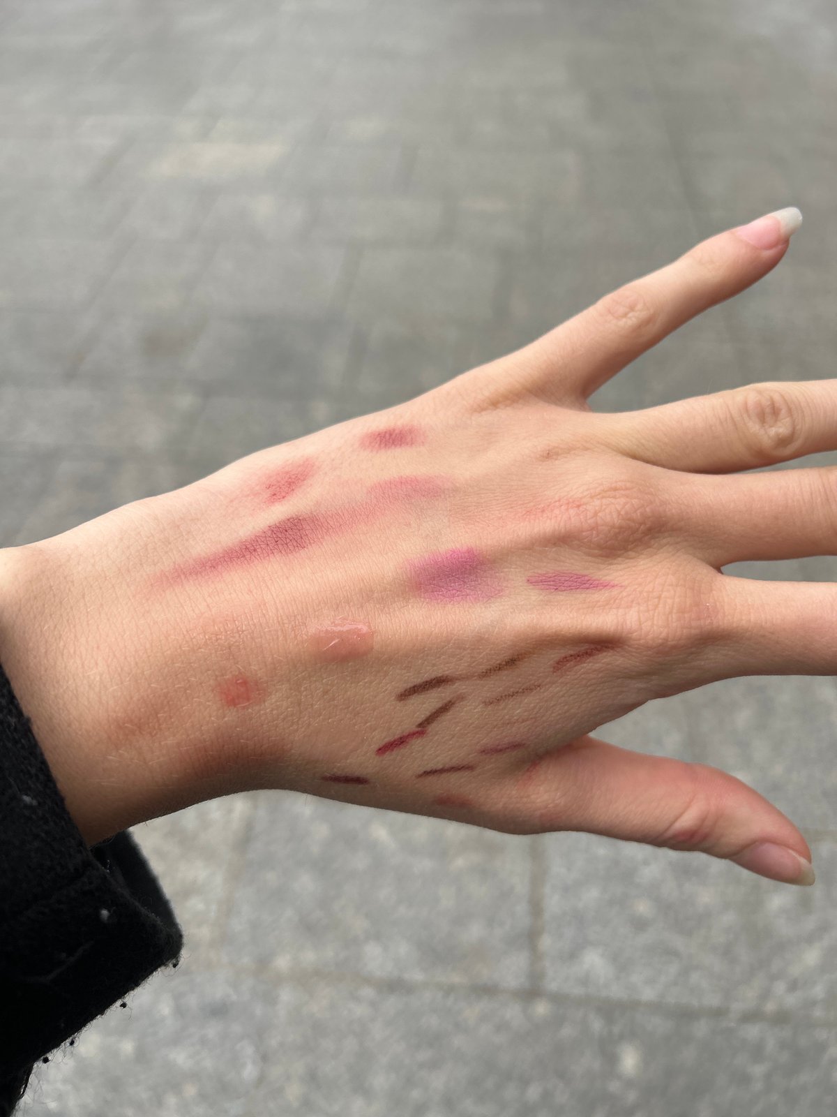 Person tests cosmetic swatches on hand in Paris