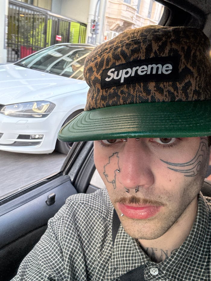 Tattooed individual spotted wearing distinctive Supreme hat in Buenos Aires