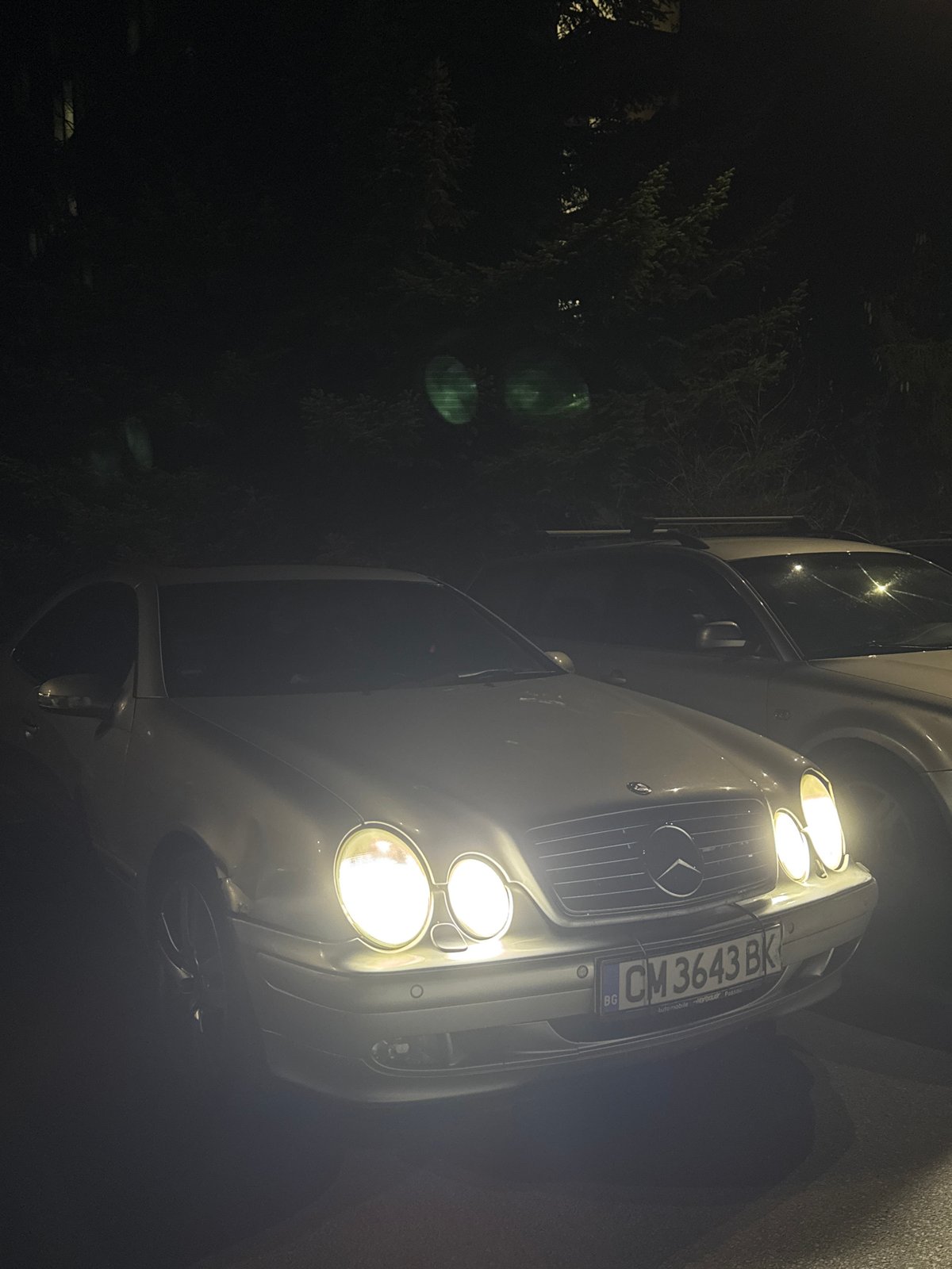 Mercedes-Benz parked with headlights on at night in Smolyan