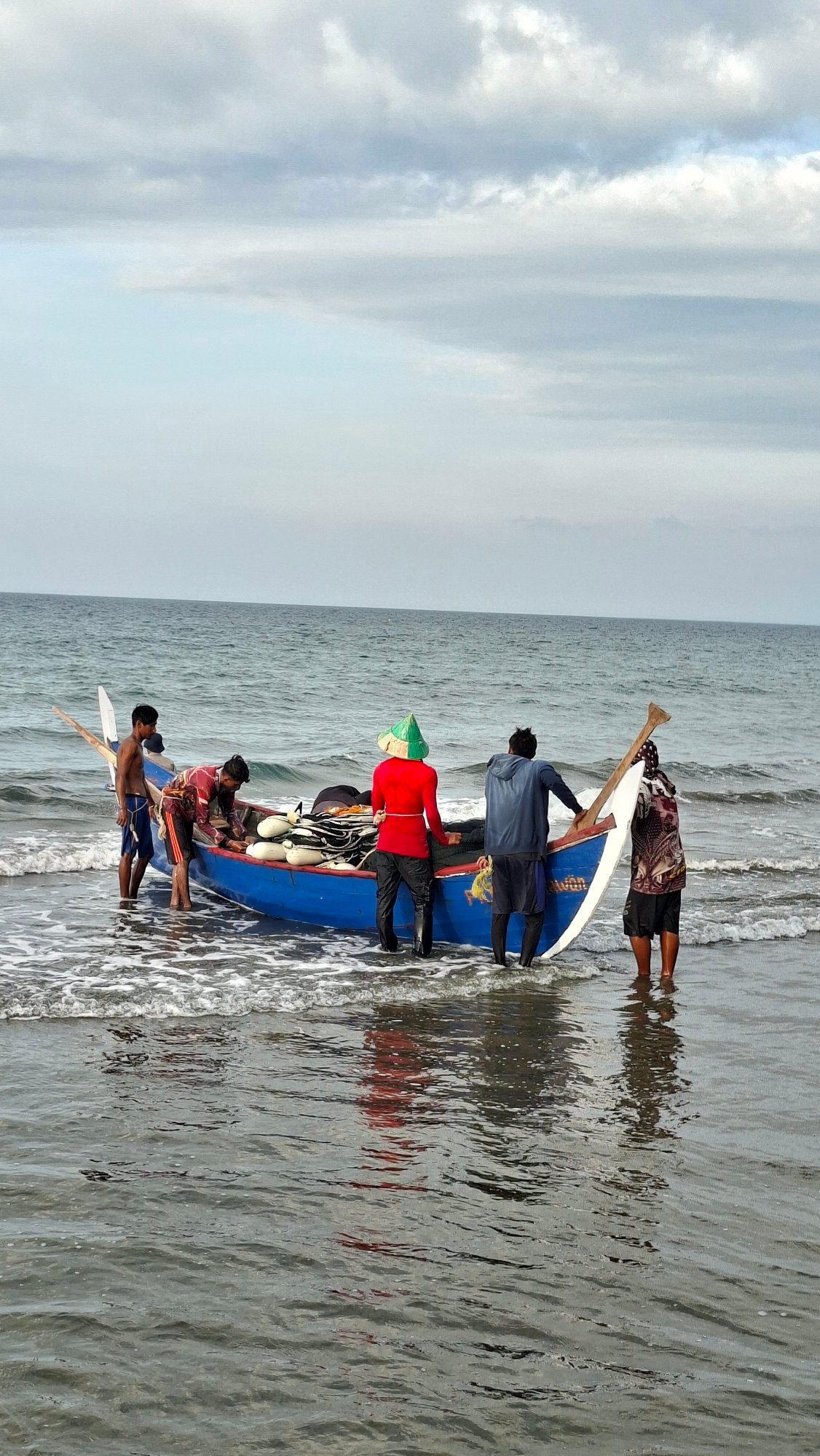 Fishermen and beachgoers share a cloudy morning in Lhokseumawe