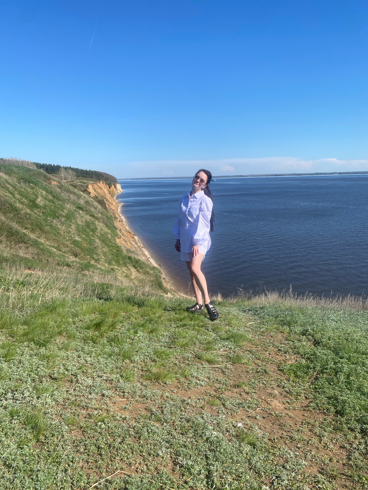 Woman stands on cliff overlooking water near Laishevo, Russia